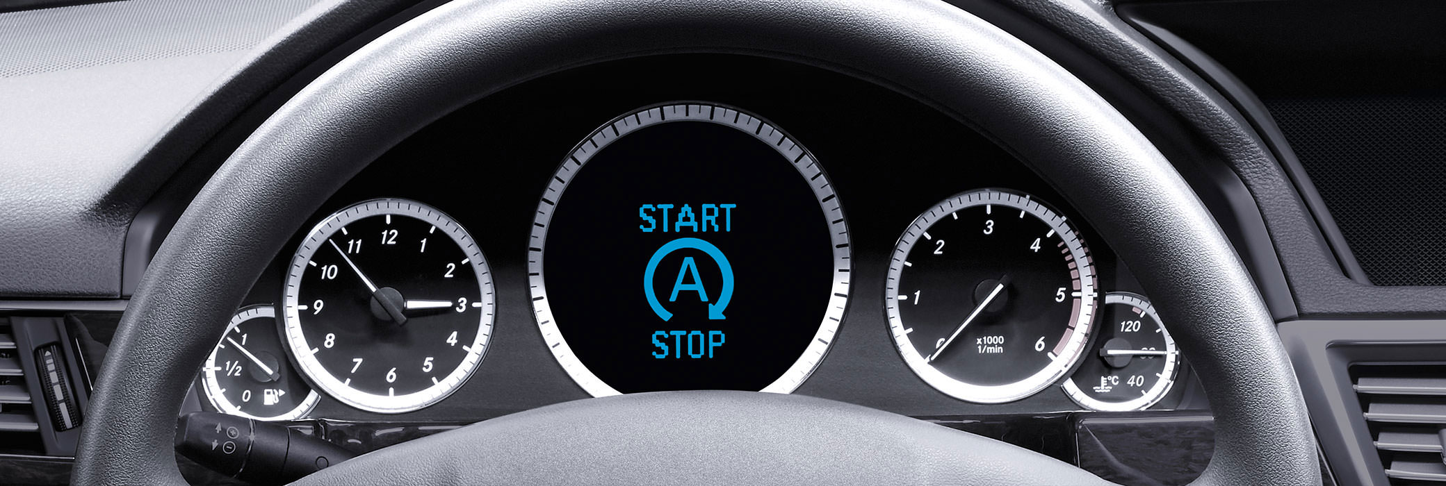 The dashboard of a car with the clock on the left side, the speed indicator on the right side and a start stop sign in the middle